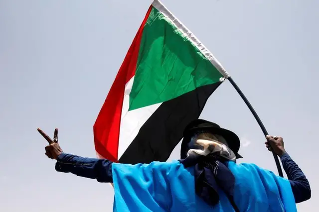 الصورة: رجل سوداني يلوح بالعلم الوطني أثناء احتفاله في شوارع الخرطوم، السودان، 5 يوليو 2019. رويترز صور / محمد نور الدين عبد الله